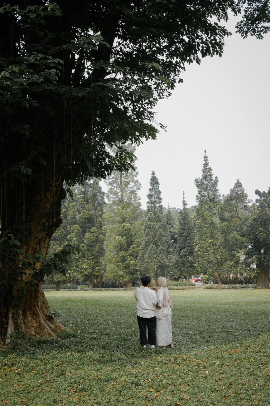 Iqbal and Deffy standing close together on a lawn beneath a great old tree.